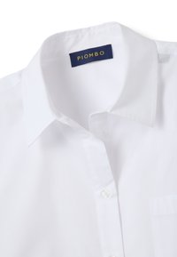 Chemise à col blanc avec une étiquette marine portant la mention "PIOMBO" cousue à l'intérieur de l'encolure.
