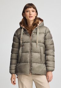 Uppblåst jacka i olivgrön färg med en glänsande yta, utrustad med huva, dragkedja fram och guldfärgad detaljer. Vadderad design med vertikala sömmar.