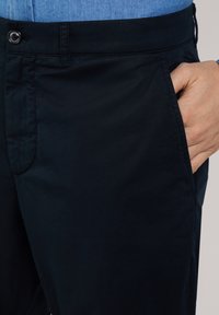 Marineblauwe katoenen broek met een slim fit, zijzakken en een sluiting met een knoop aan de voorkant, met een gladde textuur en subtiele stikseldetails.