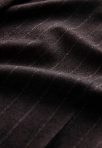 Kangas, millel on tume aluspind ja peened vertikaalsed triibud. Sile tekstuur väikese läikega, tagades rafineeritud välimuse.