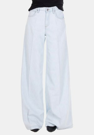 Jeans azzurri chiari a vita alta e gamba larga, indossati con scarpe nere appuntite e top nero, tagliati in vita e alle caviglie.