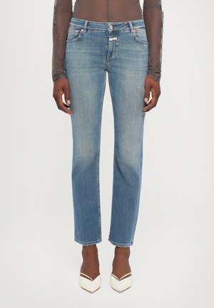 Lichtblauwe denim jeans met een rechte snit, vervaagde voorkant, vijf zakken en gestikte details. Gekleed met witte pumps met een spitse neus.