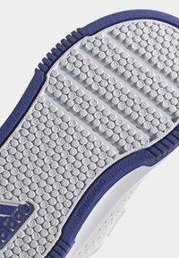 Suela de zapatilla blanca con un patrón de agarre texturizado y punteado, acentuado con un borde azul y la etiqueta "NO MARCANTE". Material de goma duradero.