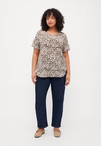 Top a maniche corte marrone e crema con un collo rotondo, abbinato a jeans blu scuro e scarpe slip-on beige.