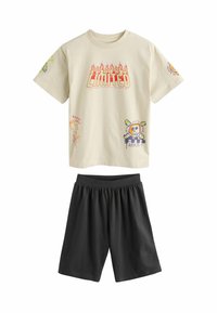 Beige bomullströja med grafiska tryck, med "LIMITED" i röda lågor. Matchad med svarta shorts med elastisk midja.