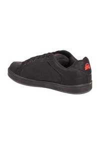 Sneaker nera con tomaia in pelle liscia, design con lacci, collo imbottito e logo di teschio rosso sul tallone. Suola in gomma piatta.