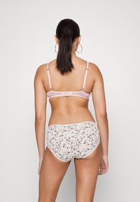 Sutiã rosa claro com alças ajustáveis e fecho de gancho, combinado com cuecas de cor creme com padrão floral; textura suave e design ajustado.
