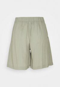 Shorts vert clair en tissu doux, dotés d'une taille élastique et d'une coupe décontractée. Design uni sans motifs ni accessoires visibles.