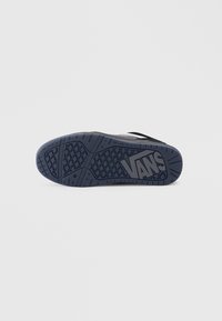 Suola in gomma nera e blu con motivo di grip testurizzato. Presenta il logo Vans in evidenza sul tallone. Forma piatta, progettata per comfort e trazione.