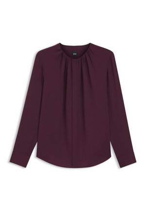 Blusa borgogna a maniche lunghe con scollo rotondo, dettaglio plissettato sul davanti e polsini con bottoni. Realizzata in tessuto morbido e leggero.