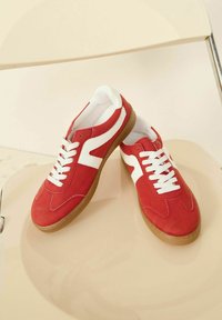 Punase nahk Converse'id valgete aktsentidega, lapikud valged paelad ja kummist valge tallaga. Ümar varvas ja minimalistik disain.