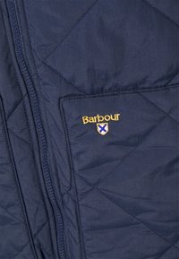 Granatowa pikowana kamizelka z ukośnym wzorem, z przednią kieszenią i złotym logo "Barbour" z emblematem w kształcie tarczy; gładka faktura, zamek błyskawiczny.