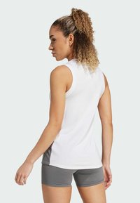 Top atlético sin mangas de color blanco con un diseño ajustado, combinado con pantalones cortos grises, que presentan una textura suave y un panel de acento lateral.