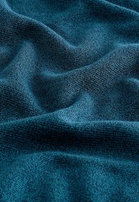 Structuriertes, türkisfarbenes Gewebe mit einer weichen, gestrickten Optik, das Wellen und subtile Farb- und Tiefenvariationen zeigt.