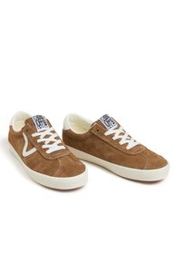 Braune Wildleder-Sneaker mit weißen Schnürsenkeln und Gummisohlen. Sie verfügen über ein erhabenes Logoschild an der Zunge und kontrastierende Nähte.