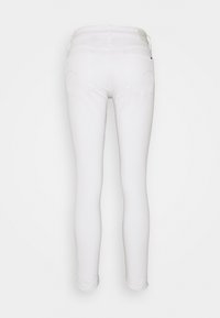 Jeans blancos ajustados con una textura suave, que presentan dos bolsillos traseros y una cintura estándar. Hechos de tela de mezclilla, sin hardware visible.