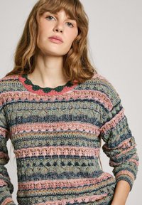 Pull en tricot multicolore avec un col rond, présentant des rayures verticales en rose, vert et bleu avec des motifs texturés.