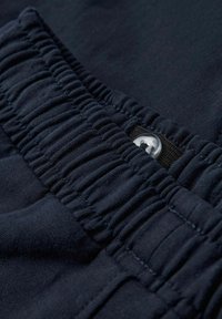 Fascia elastica blu navy con texture arricciata, dotata di un bottone argentato e un supporto in tessuto nero per una chiusura sicura, materiale morbido.