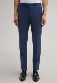 Schlanke, marineblaue Hosen aus strukturiertem Stoff, mit klaren Linien, flacher Vorderseite und glattem Bund, kombiniert mit eleganten, schwarzen Schuhen.
