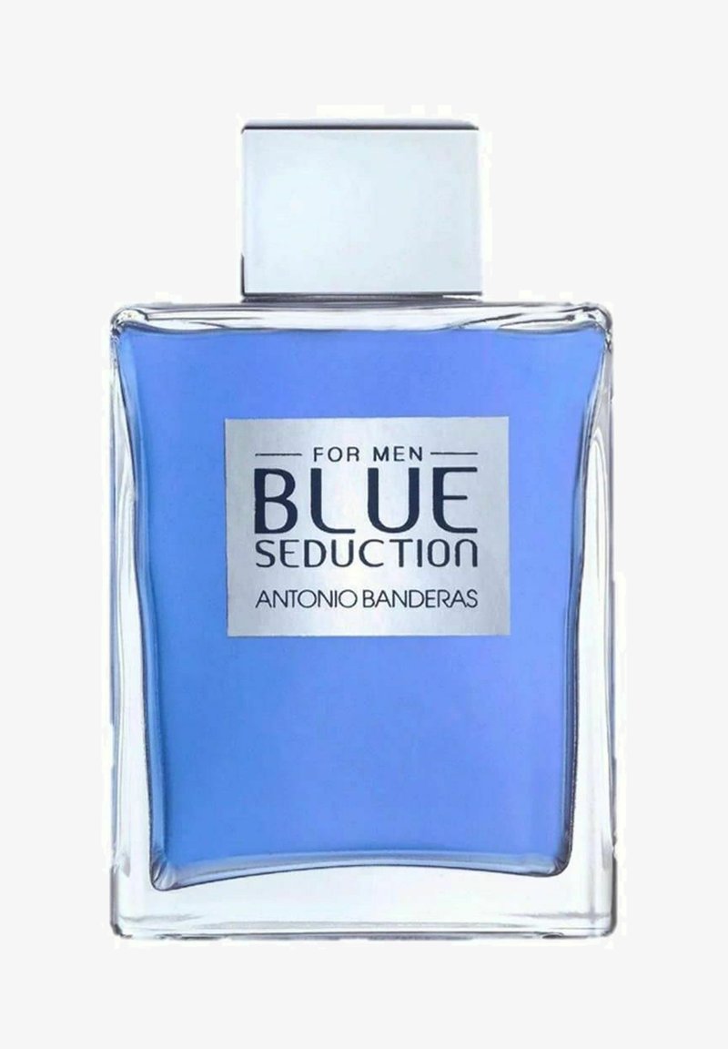 Transparent rektangulär glasflaska med ett silverfärgat fyrkantigt lock, innehållande ljusblå vätska. Framtida etikett anger "BLUE SEDUCTION FOR MEN ANTONIO BANDERAS."
