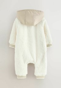 Witte fleece eendelige outfit met een beige capuchon, voorzien van ribbelmanchetten met gouden strepen. Zachte textuur, ontspannen pasvorm en geen sluitingen.