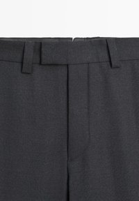 Pantalon gris foncé en tissu texturé, avec un devant plat, des passants pour ceinture et deux plis avant. Aucun élément métallique ni motif visible.