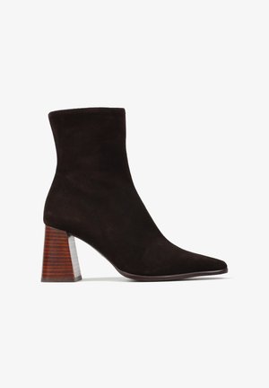 Czarne zamszowe botki za kostkę z szpiczastym noskiem, z paskowym drewnianym obcasem. Gładka faktura i dopasowany krój zapewniający osłonę kostki.