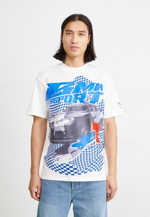 White cotton t-shirt featuring a graphic of a car, blue and red accents, checkered patterns, and bold text. Short sleeves and relaxed fit.