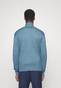 Maglione lavorato a maglia blu testurizzato con collo alto e polsini a costine, con vestibilità comoda e motivo dettagliato, mostrato da dietro.