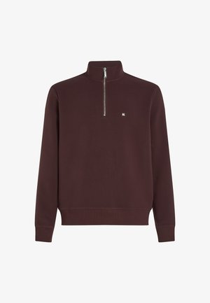 Burgundski pulover s kratkim zadrgo, z rebrastimi manšeti in robom ter majhnim belim logotipom na prsih. Narejen iz mehkega materiala.