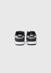 Fekete és szürke Nike sportcipők texturált felsőrésszel, fehér középtalppal, fekete gumitalppal és kontrasztos szürke díszítésekkel az oldalán.