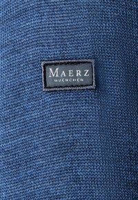 Tessuto a maglia blu navy con una finitura testurizzata e un'etichetta intrecciata che mostra "Maerz Muenchen" in bianco su sfondo nero.