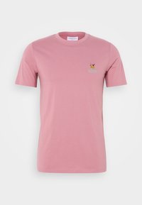 T-shirt en coton rose à manches courtes, col rond, avec un petit motif brodé sur la poitrine. Texture lisse et coupe classique.