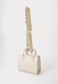 Beige Handtasche mit strukturiertem Oberflächen-Muster und Logo, Doppelgriffe und einem abnehmbaren Trageriemen. Akzente in goldfarbener Hardware.