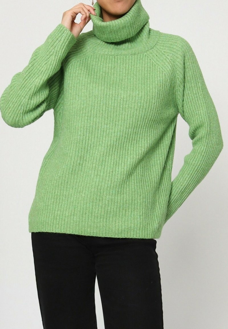 Pull à col roulé côtelé vert avec manches longues et coupe décontractée, présentant un tissu texturé et des fentes sur les côtés.