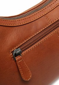 Braune Lederhandtasche mit einem Reißverschluss und einem Metallschieber, detaillierten Nähten und einer glatten Oberfläche. Die Tasche hat eine halbgebogene Form.