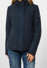 Navy fleece jacket with quilted front panel and high collar. Features side pockets and adjustable toggles at neckline. Casual fit.