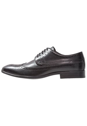 Chaussure habillée pour homme en cuir noir avec détails brogue, lacets et talon bas, montrée de profil sur fond blanc.