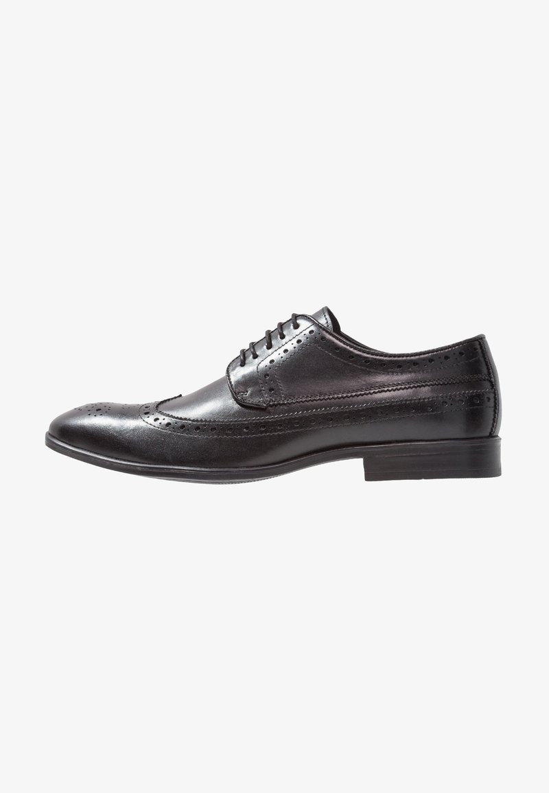 Chaussure habillée pour homme en cuir noir avec détails brogue, lacets et talon bas, montrée de profil sur fond blanc.