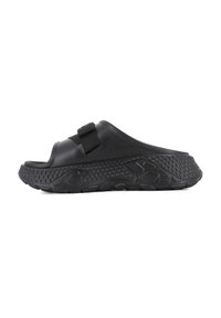 Black slide sandal featuring a textured strap and sole, with a thick, contoured footbed and a rubberized, patterned base for traction.
