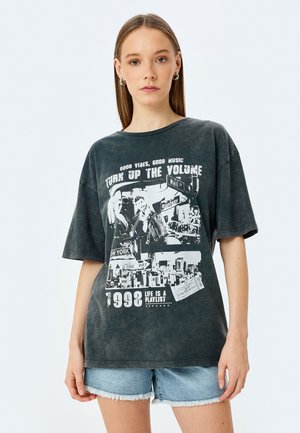 T-shirt surdimensionné gris foncé en coton doux avec un lavage vieilli. Comprend des impressions graphiques, y compris du texte et des images de paysages urbains, datant de 1998.