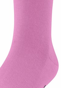 Primo piano di una calza rosa brillante, che mette in risalto la sua texture liscia e il motivo a coste, con un piccolo logo nero visibile vicino all'unghia.