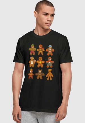 Black t-shirt featuring cartoon gingerbread superheroes with colored accents, arranged in two rows, detailed with facial expressions and costumes.