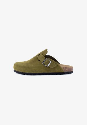 Sabots en suède vert olive avec une seule boucle ajustable, semelle en liège et semelle extérieure en caoutchouc noir texturé. Design simple à enfiler.