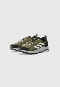 Trail running shoes in olive green and black. Features include a breathable mesh upper, reflective accents, and rugged rubber outsole.
