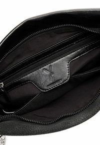 Intérieur d'un sac en cuir noir texturé avec une poche zippée doublée de tissu et une étiquette de marque Suriffrey embossée.