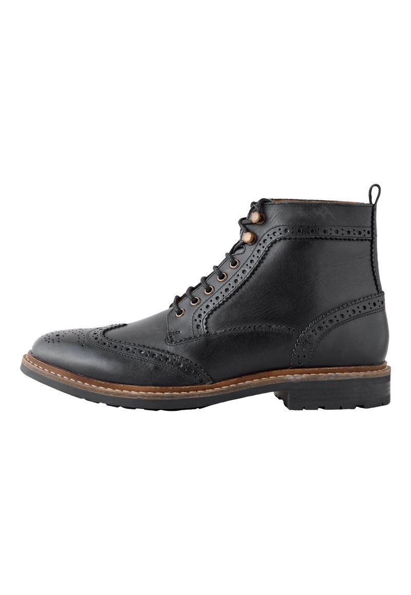 Schwarzer Leder-Stiefelette mit Brogue-Details, Schnürsenkeln mit Metalldringen und einer strukturierten Sohle mit kontrastierendem braunem Rand.