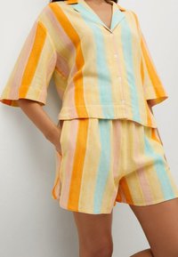 Leinen-Loungewear-Set mit kurzärmeligem Hemd zum Knöpfen und passenden Shorts. Vertikale Streifen in Orange, Gelb, Pink und Blau.