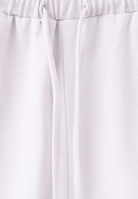 Ceinture blanche en coton avec cordon de serrage et fronces élastiques sur un tissu doux, probablement partie d'un pantalon décontracté ou d'un short.