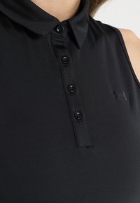 Černé sleeveless polo tričko má límec se zapínáním na knoflíky s šesti černými knoflíky a texturovanou látku. Logo viditelné na levé straně hrudi.